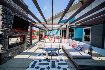 A modern outdoor living space with a stone fireplace and a white sofa.
